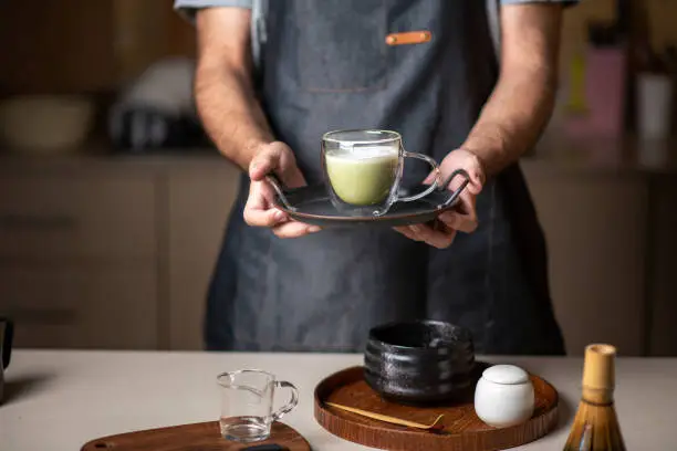Photo of Man offering fresh matcha latte green tea beverage