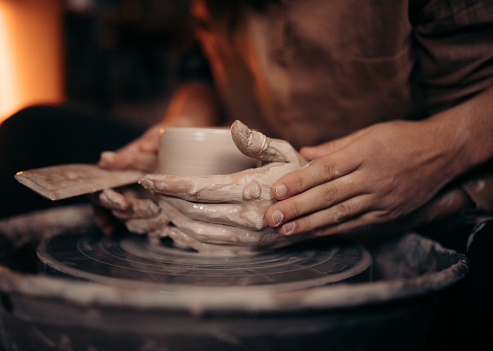 Couple shaping jar with special tool in pottery workshop