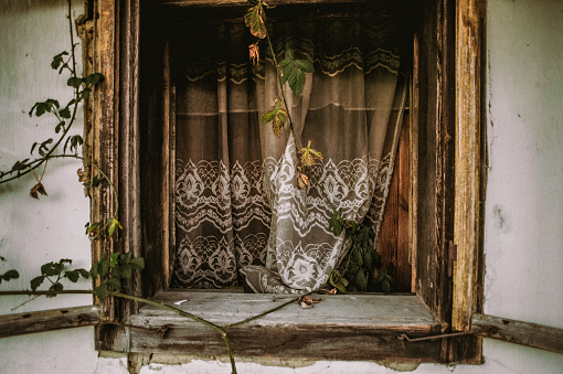 Old weathered window with lace curtain