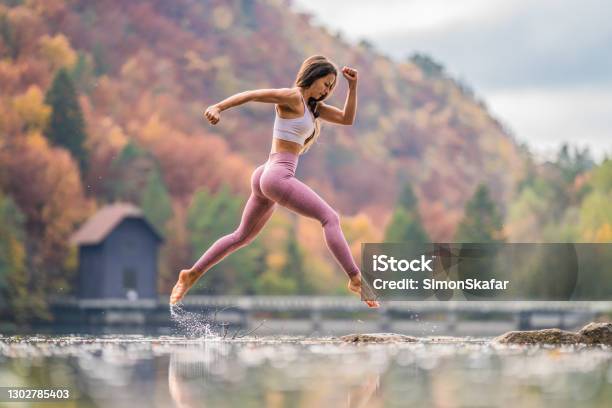 Young Woman Jumping Over Water In The Nature Stock Photo - Download Image Now - Exercising, Women, Jumping