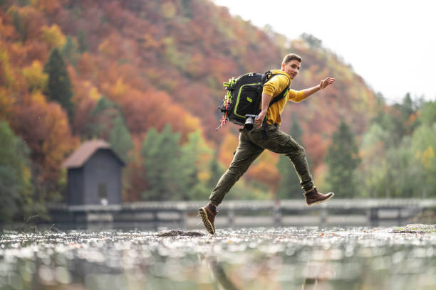Young cameraman jumping over water
