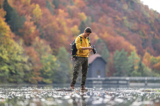 male photographer holding camera in lake - nature photographer imagens e fotografias de stock