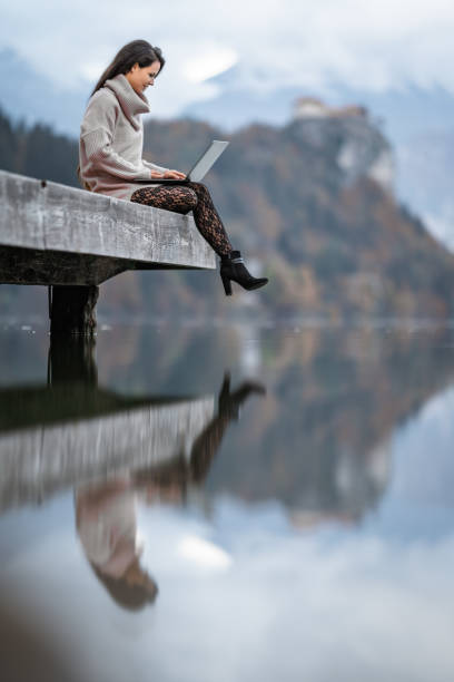 istock Young woman using laptop on pier 1302785467