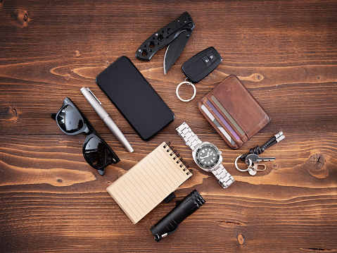 Flat lay of men's EDC or Every Day Carry items and tools on wooden background