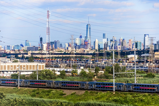 Power lines and a commuter train in New Jersey with the New York City downtown skyline in the background.