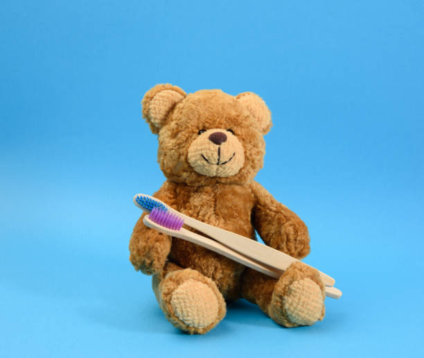 istock brown teddy bear with a wooden toothbrush on a blue background 1302790374