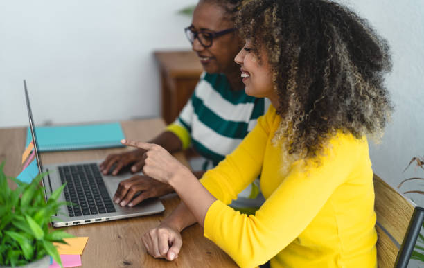 istock Afro Mother and daughter having fun using computer for shopping online - Youth and elderly people with technology concept 1302792270