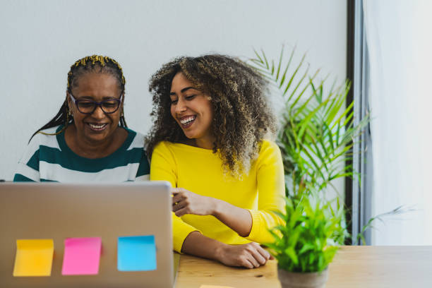 Afro Mother and daughter having fun using computer for shopping online - Youth and elderly people with technology concept