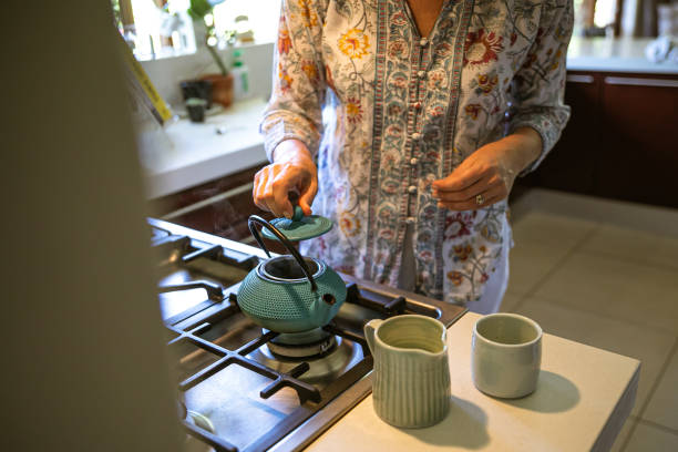 istock Woman placing lid on cast iron teapot 1302795386