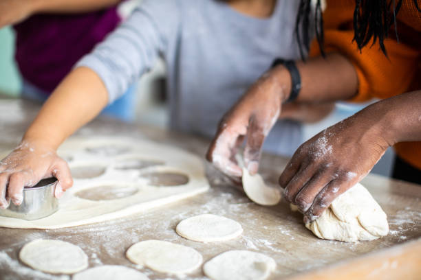 istock Mother and daughters preparing cookies in kitchen at home 1302795471