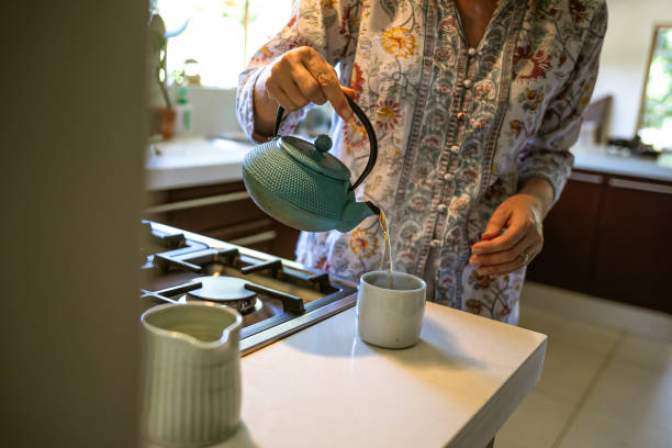 istock Woman pouring black tea from cast iron teapot 1302797278