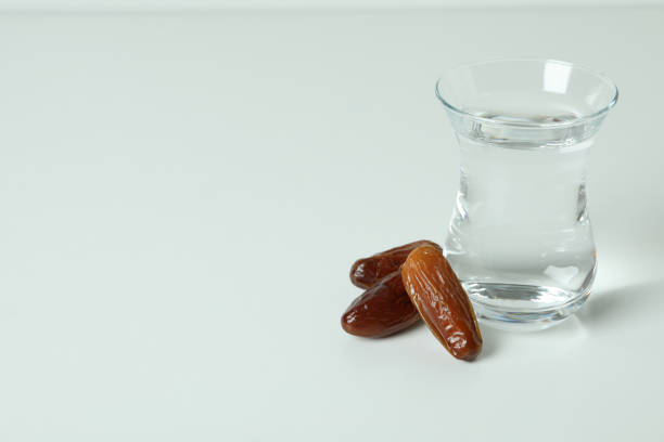 istock Glass of water and dates on white background 1302797623