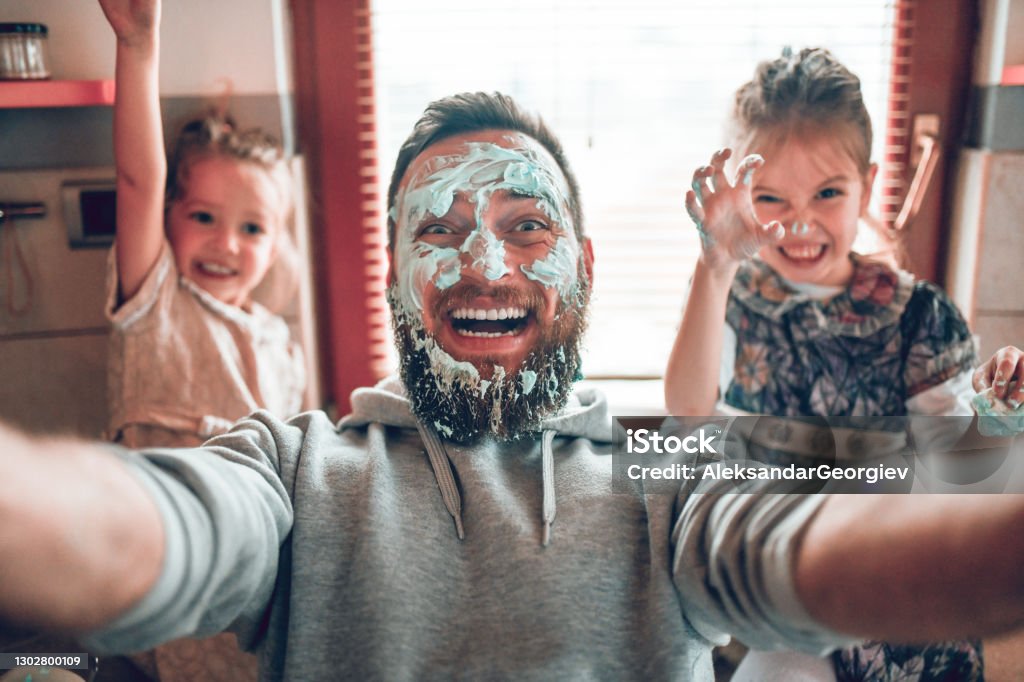 Selfie por padre con lindas hijas infantiles después de cocinar y hacer líos con la cobertura - Foto de stock de Padre libre de derechos