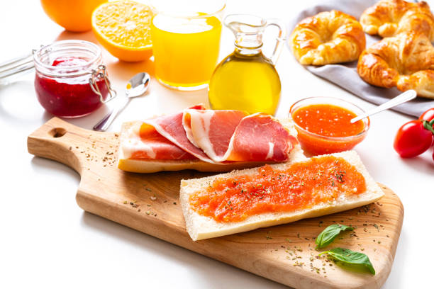 Mediterranean breakfast on white table Spanish tomato and ham toast, croissant, orange juice, olive oil. Traditional Mediterranean breakfast or lunch on white background. High resolution 42Mp studio digital capture taken with SONY A7rII and Zeiss Batis 40mm F2.0 CF lens spanish breakfast stock pictures, royalty-free photos & images