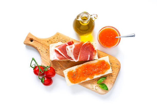Breakfast: Spanish tomato and ham toast with olive oil shot from above Tomato and ham toast, Traditional Spanish breakfast shot from above on white background. High resolution 42Mp studio digital capture taken with SONY A7rII and Zeiss Batis 40mm F2.0 CF lens spanish breakfast stock pictures, royalty-free photos & images
