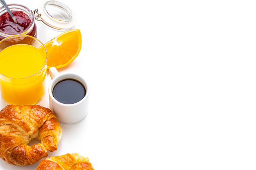 Breakfast: croissants, orange juice, coffee and marmalade on white background. Copy space