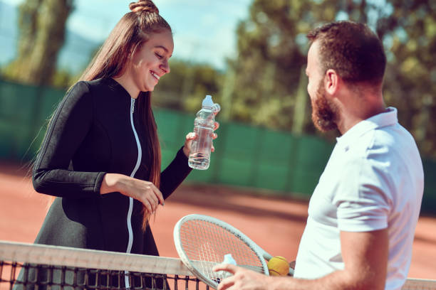 süßetennis paar trinkwasser nach spiel - tennis court love victory stock-fotos und bilder