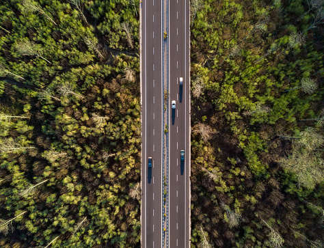 View from above, stunning aerial view of some cars running along a road flanked by a beautiful forest. Sardinia, Italy.