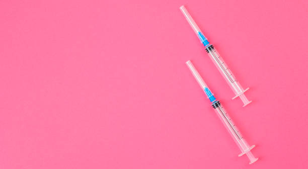istock Two syringes on pink background. Coronavirus vaccine and injections concept. 1302805143