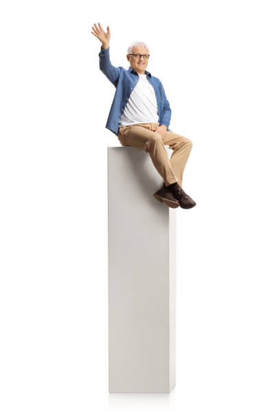 istock Smiling mature man sitting on a column and waving at camera 1302807509