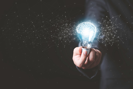 Businessman holding glowing lightbulb with drawing brain and connection line, creative thinking ideas and innovation concept.