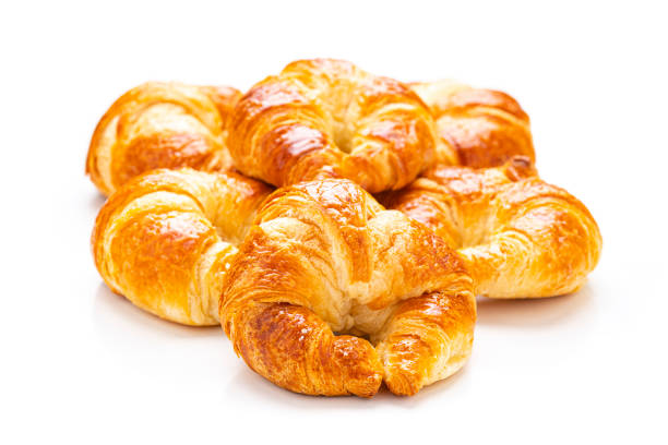 Close up view of fresh homemade croissants heap isolated on white background. Predominant colors are yellow and white. High resolution 42Mp studio digital capture taken with Sony A7rII and Sony FE 90mm f2.8 macro G OSS lens