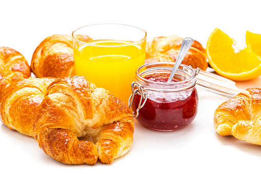 Breakfast: croissants, orange juice and marmalade on white table. Predominant color is yellow. High resolution 42Mp studio digital capture taken with Sony A7rII and Sony FE 90mm f2.8 macro G OSS lens