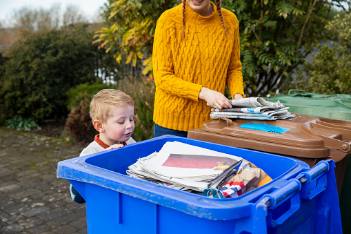 Mother helping her young son recycle newspapers at their home in the North East of England.