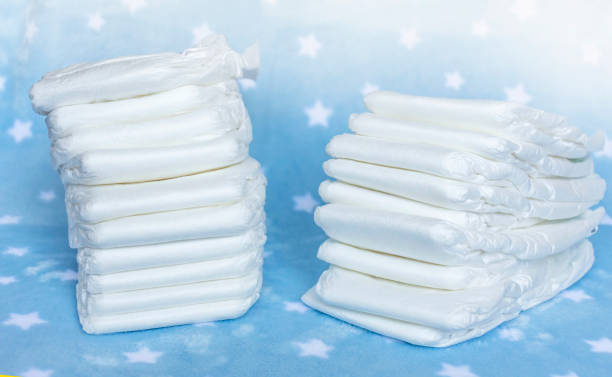 istock Stack of white disposable diapers for little babies on nice blue background with stars. Selective focus 1302810825