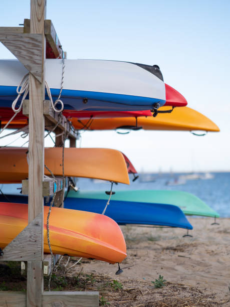 Colorful image of several kayaks stored on the beach.