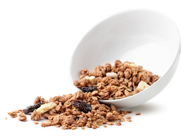 granola z rodzynkami i bananem wylewającym się z talerza na białym tle. izolowane - bowl cereal cereal plant granola zdjęcia i obrazy z banku zdjęć