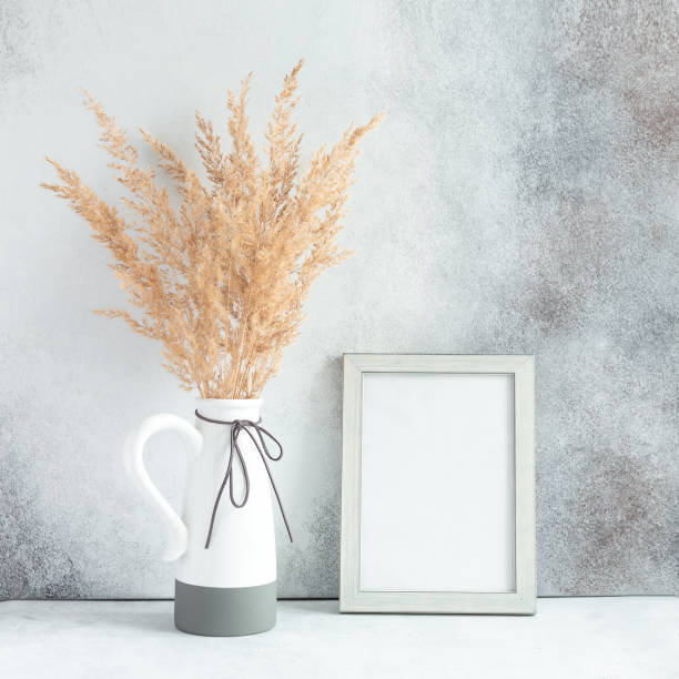 istock Pampas grass in ceramic vase and empty photo frame against wall. Minimalistic Scandinavian style 1302817550