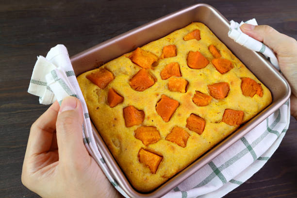 Hand Holding Fresh Baked Butternut Squash Cake with Kitchen Cloth Placing on Wooden Table