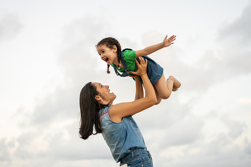 A portrait of young mother with a small daughter in summer nature. Mother Love Portrait.