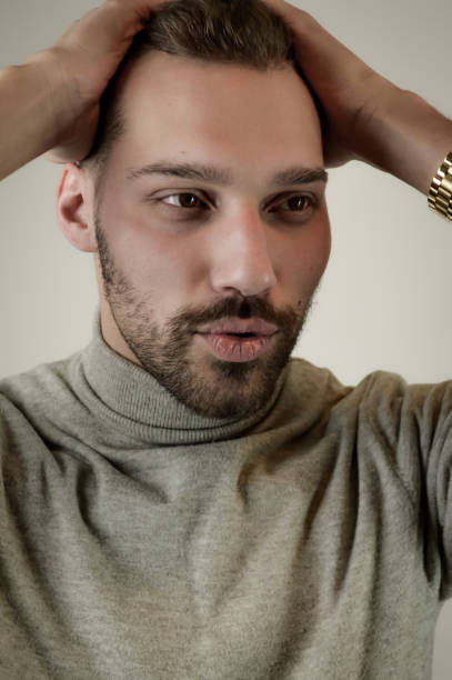 Young man with a short beard with his hands on the head looks surprised