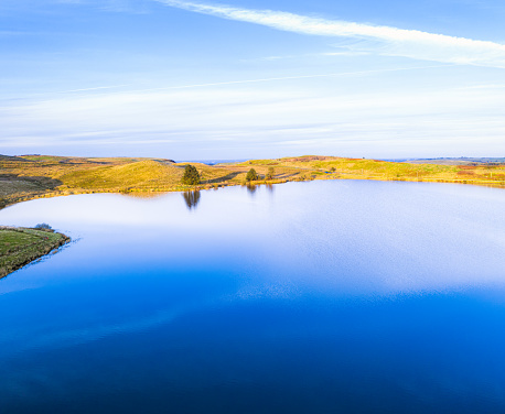 An aerial image of a blue summer sky reflected in the water of a small lake.