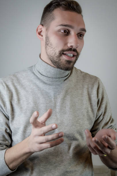 istock Young man with a short beard speaks gesturing with his hands to explain something 1302819728