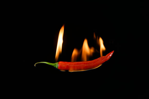 istock Red hot chili pepper on black background with flame 1302819770