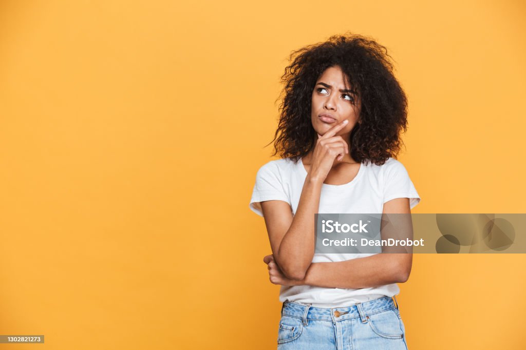 Portrait of a thoughtful young african woman Portrait of a thoughtful young african woman looking away at copy space isolated over beige background Contemplation Stock Photo