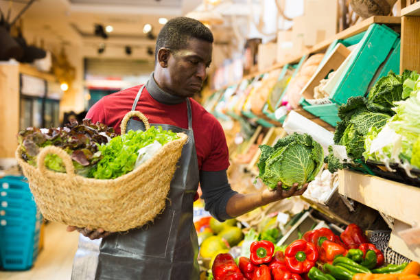 istock Man putting greens and vegetables on market showcase 1302822710