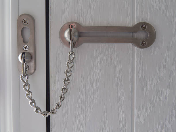 Door security chain on domestic door, North Yorkshire, England, Britain, February 2021 Crime prevention measure on household door door chain stock pictures, royalty-free photos & images