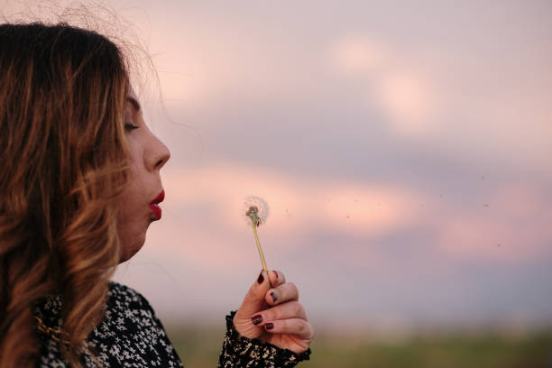 istock Young woman blowing a dandelion 1302824659