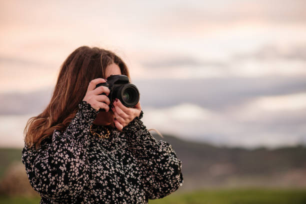 istock Young woman taking a picture with a DSLR camera 1302824788