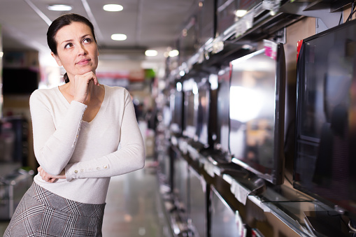 Woman selecting television set in  household appliances  store