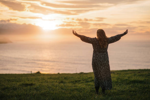 istock Young woman with arms raised at sunset 1302825352