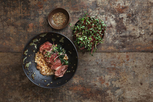 Grilled Venison Steak with Spelt Grain Grilled venison steak with spelt grain and microgreen. Flat lay top-down composition on dark background. danish culture photos stock pictures, royalty-free photos & images