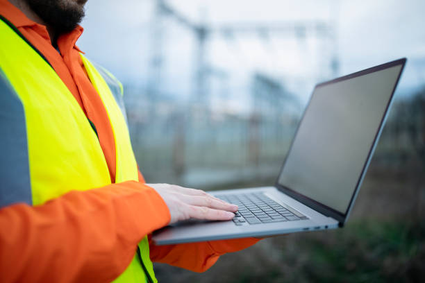istock Confident male engineer using a laptop in front of electric power station. 1302827049