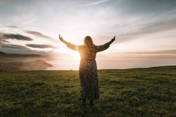 istock Young woman with arms raised at sunset 1302827102