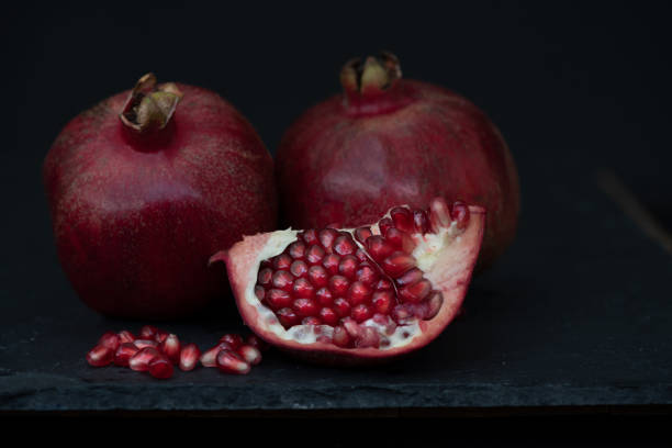istock pomegranate fruits against wooden table 1302828129