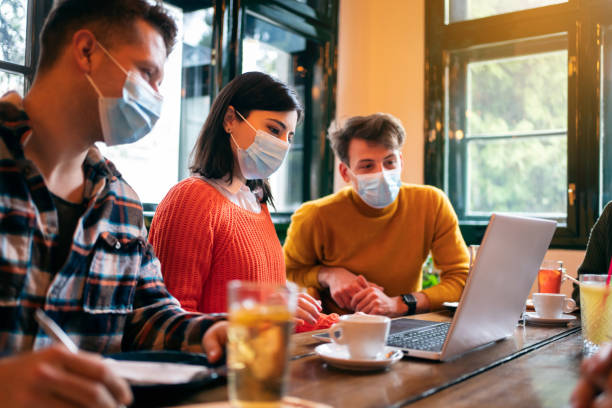 istock Three young diverse people with protective face masks having a business meeting in a restaurant 1302828407